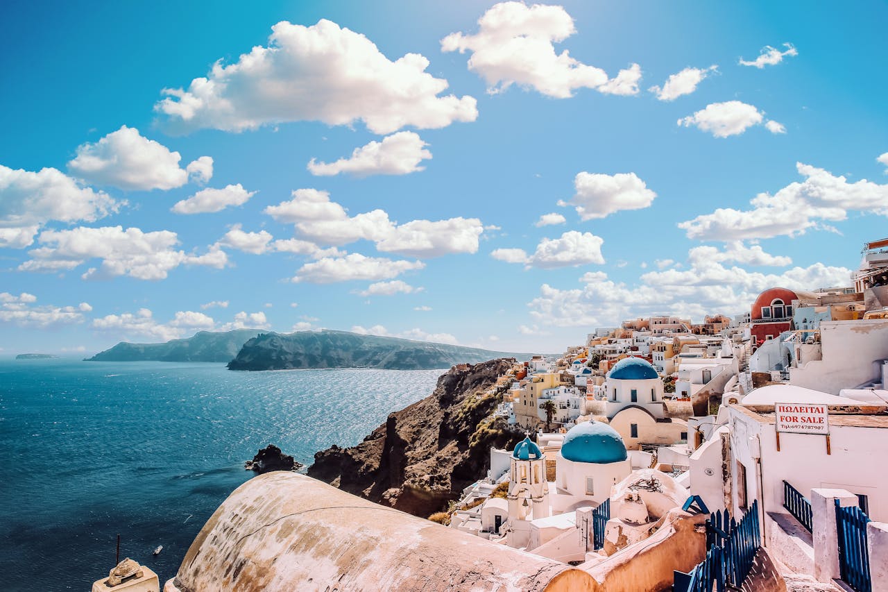 services-03 Captivating view of Santorini's famous blue-domed buildings under a vibrant sky.